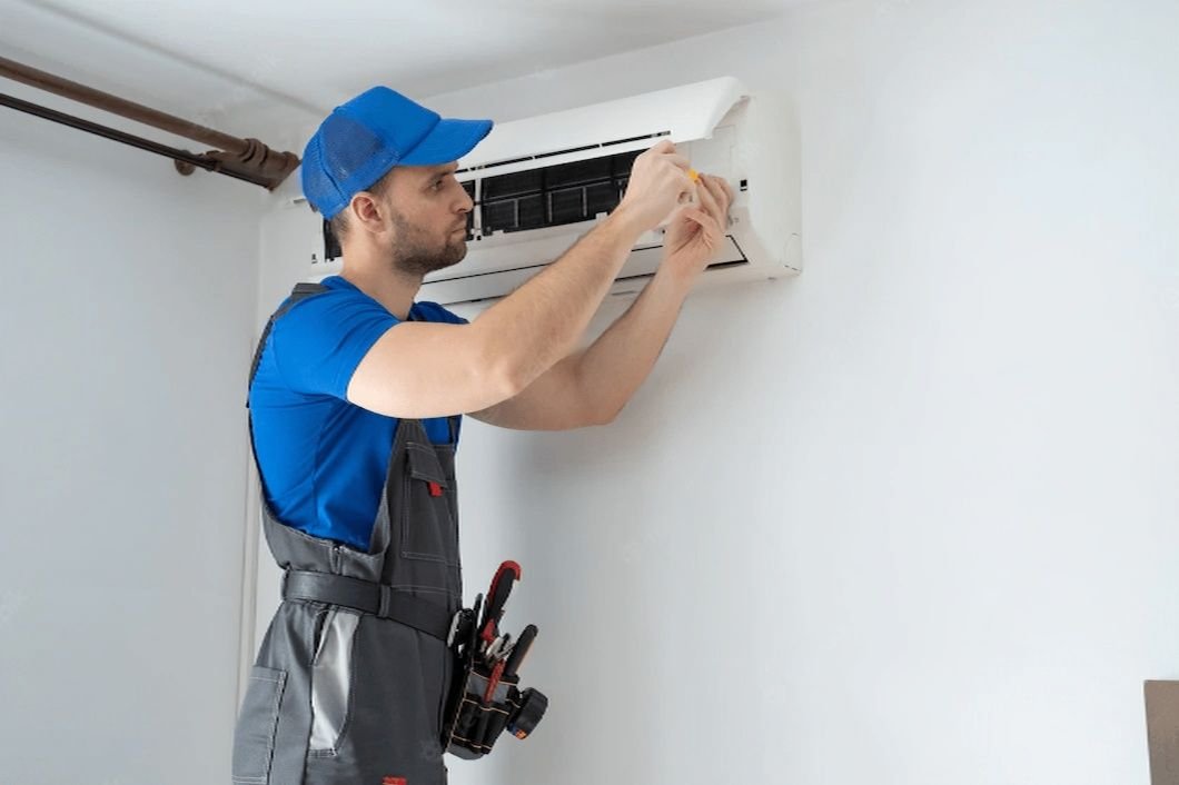male technician in overalls and a blue cap repairs an air conditioner on the wall 353017 466 transformed